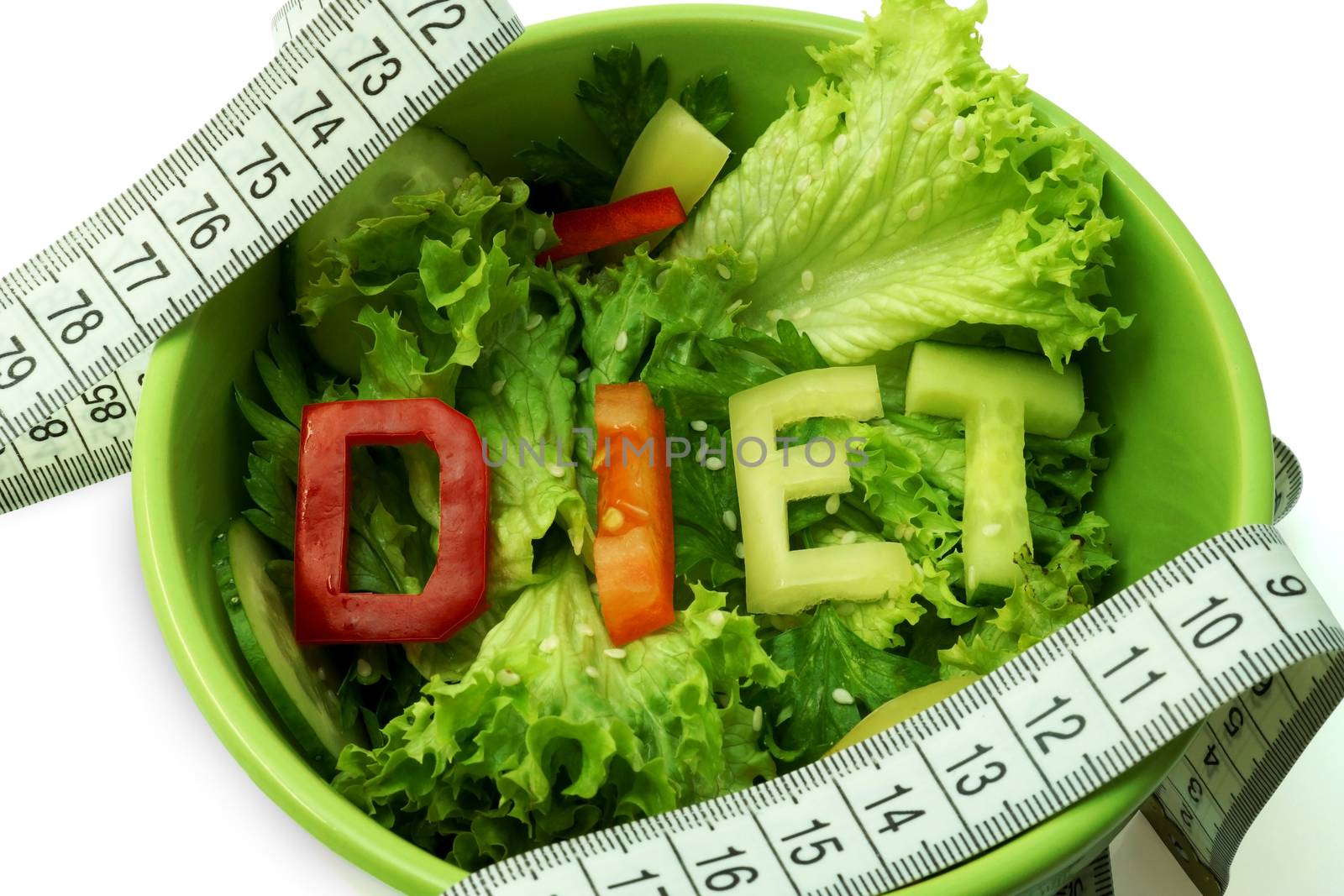 Green plate with word diet composed of slices of different vegetables on salad