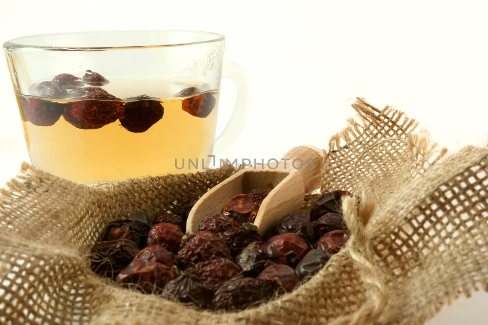 Herbal medicine. Cup of herbal tea with dried rose hips in a sack