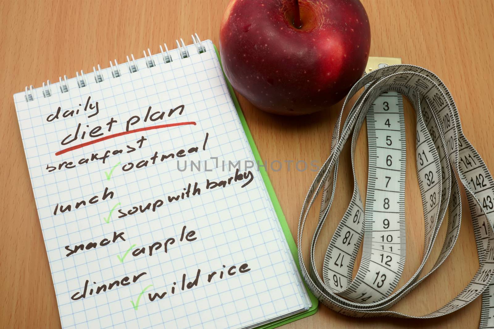 Planning of a diet. Measuring tape, apple and a notepad with a daily diet plan