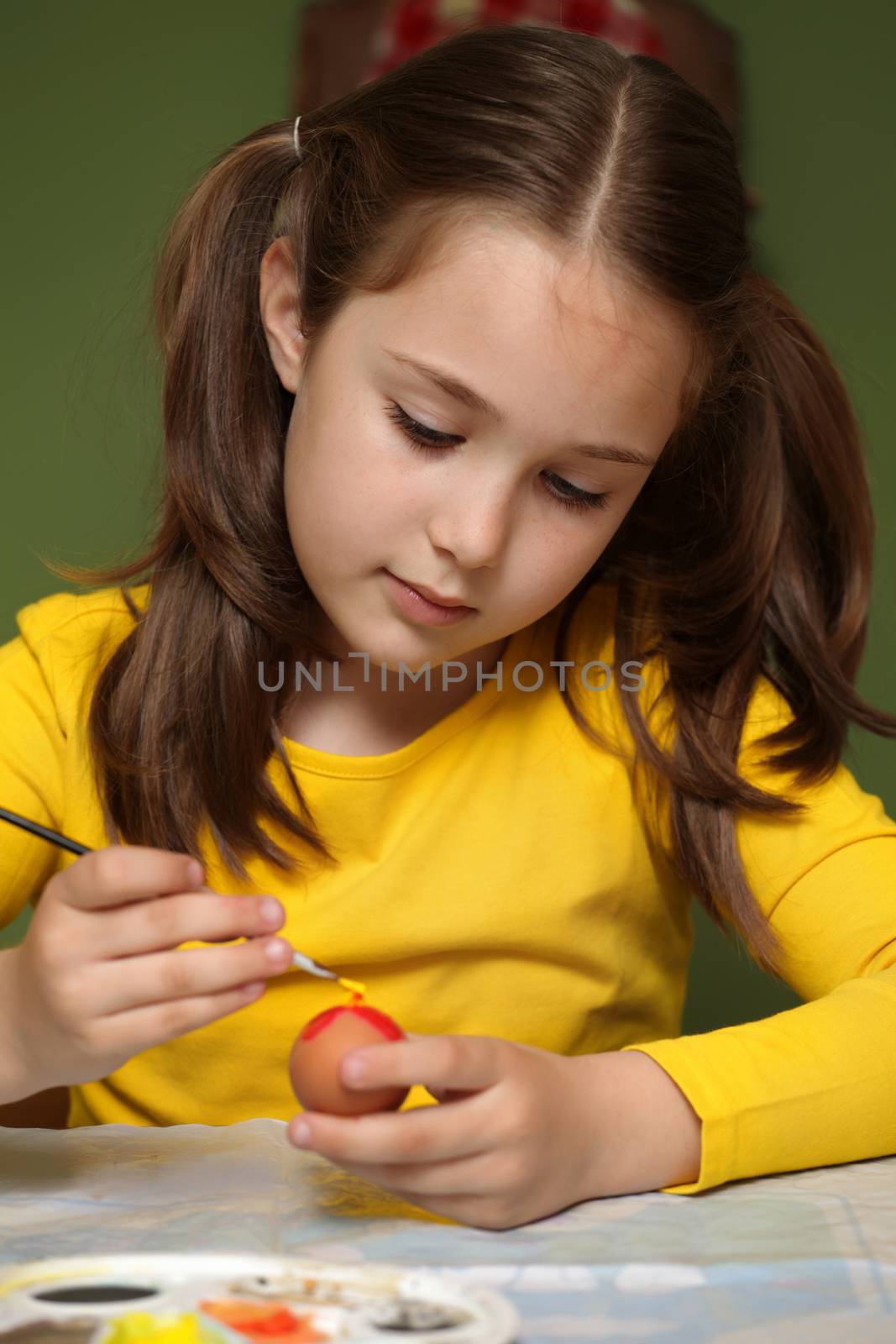 Girl painted Easter eggs at the table