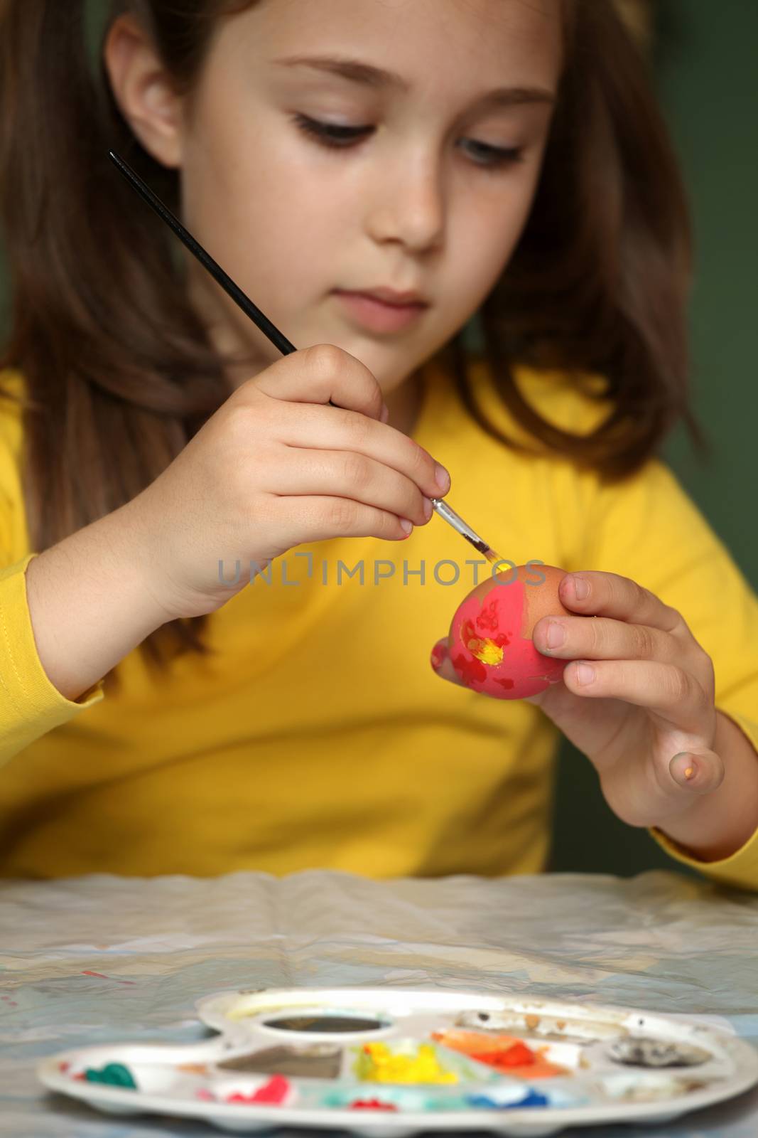 Girl painted Easter eggs at the table