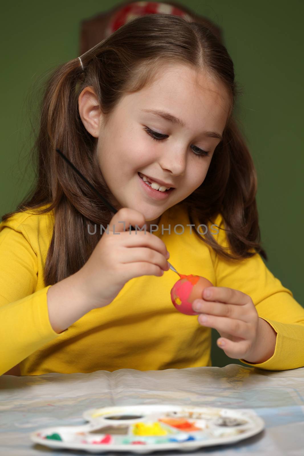 Girl painted Easter eggs at the table 