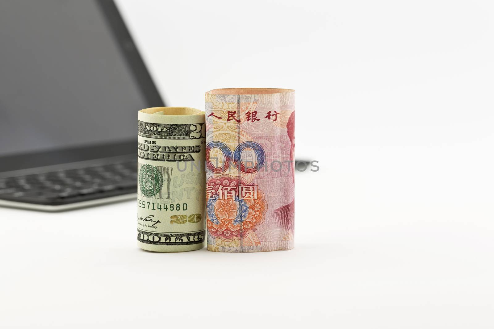 American dollar and Chinese yuan currencies in front of tablet screen and keyboard reflect global trends of investment in technology