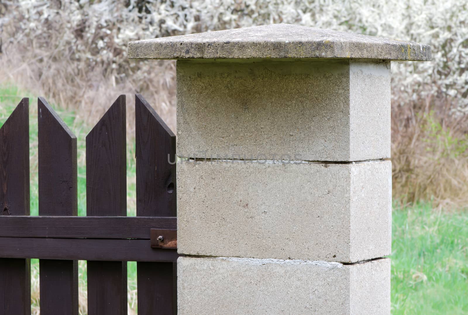 Concrete blocks side post of brown wooden fence.