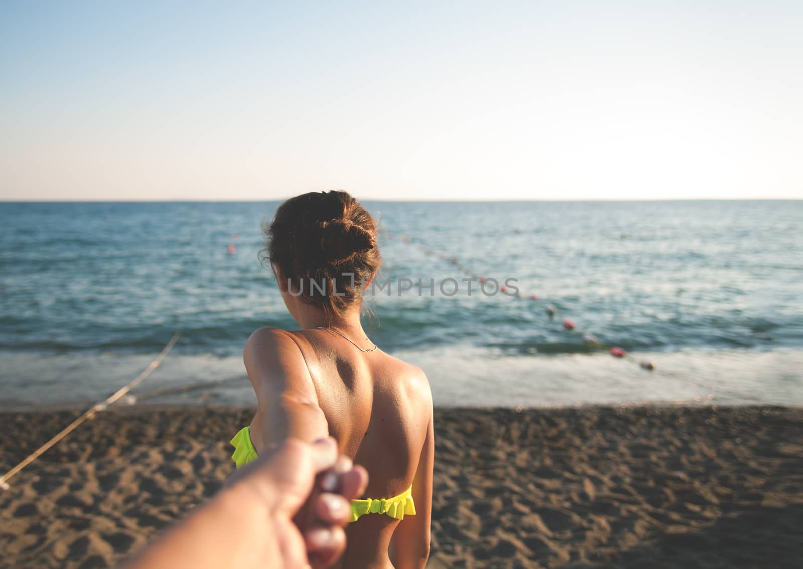 Girl at the sea holding the hand of Man.