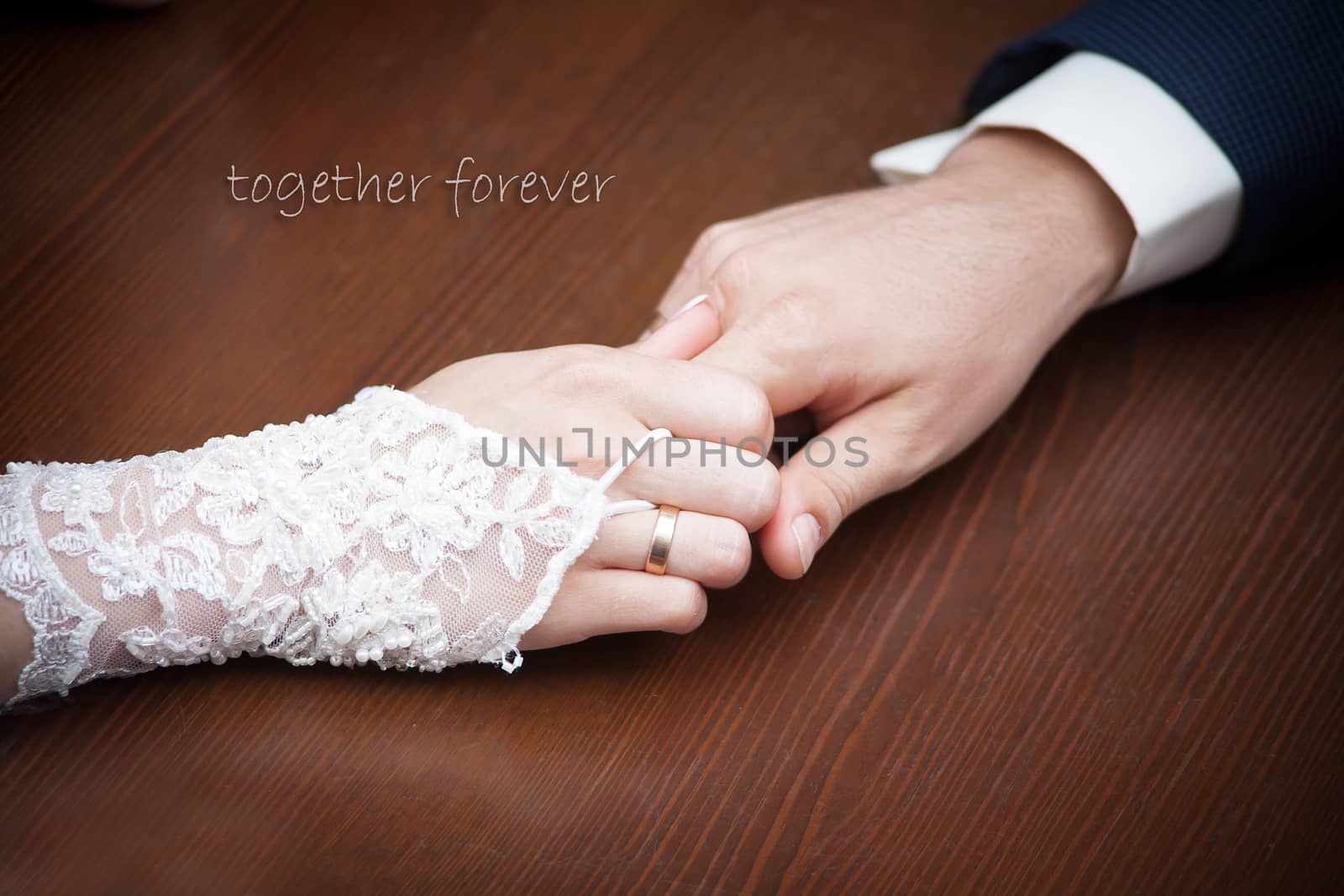 Bride and groom holding hands on wood background by sfinks