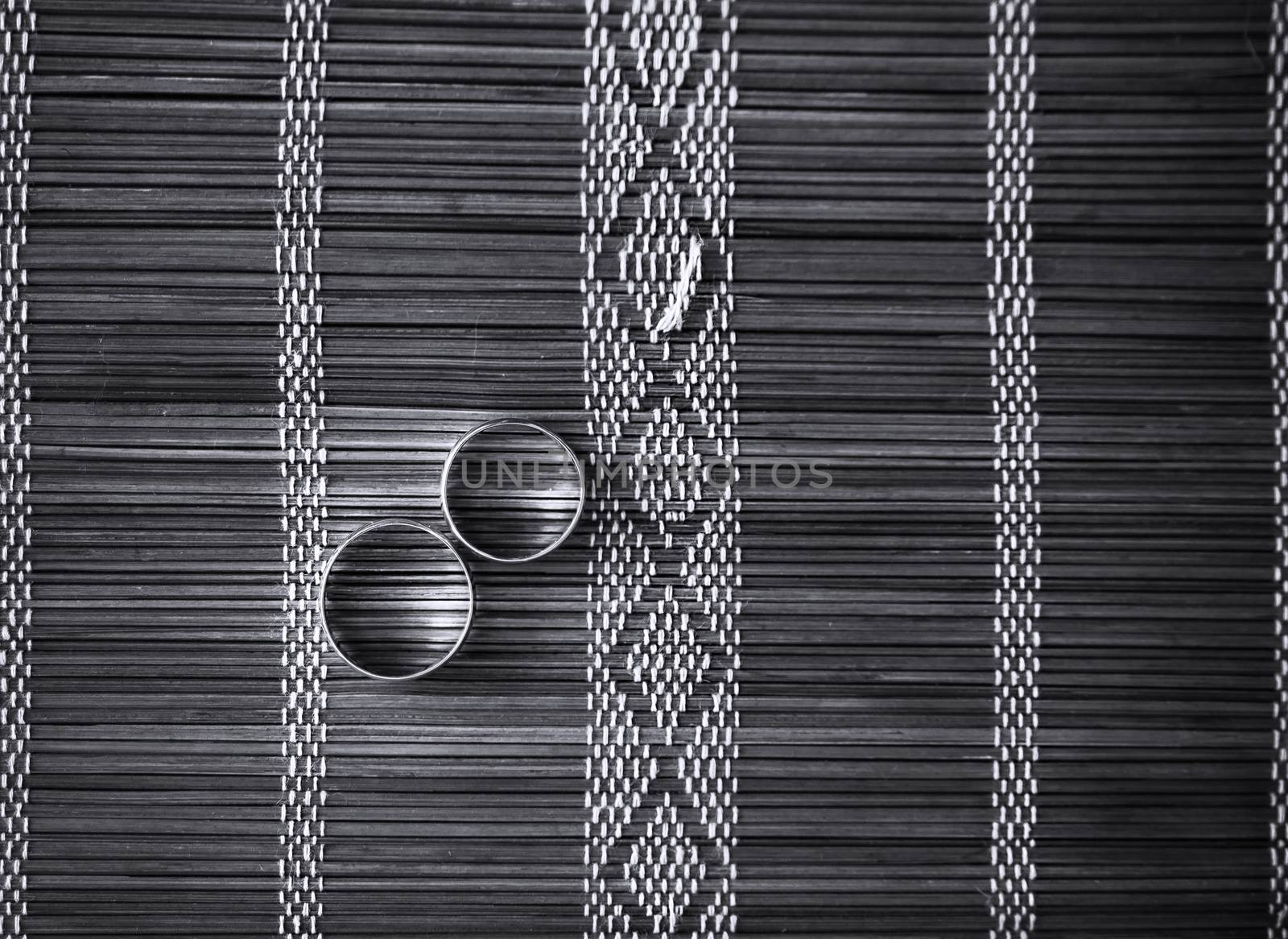 Two wedding rings on bamboo mat. Black and white photo.