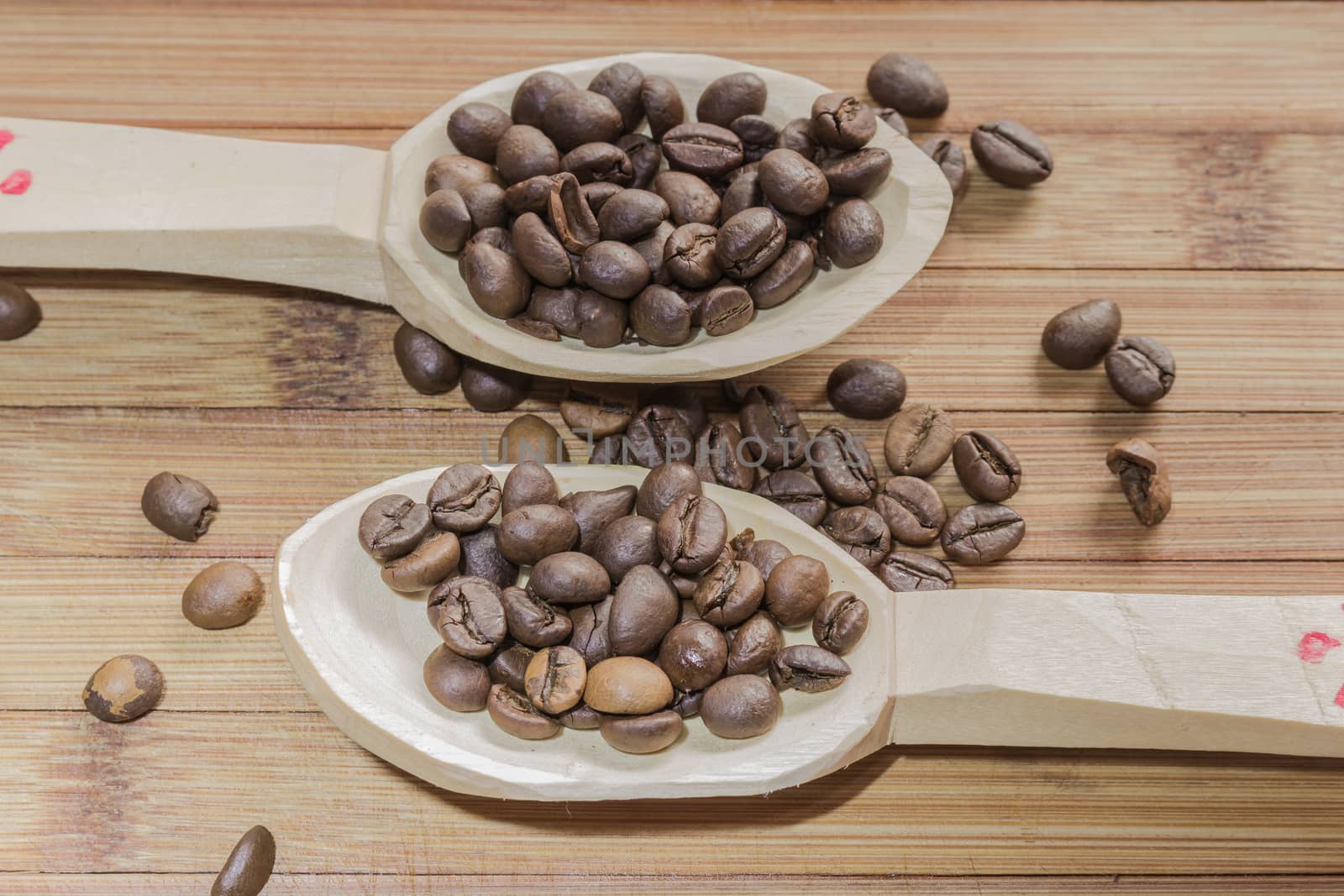 Coffee beans and two wooden spoon on wooden background