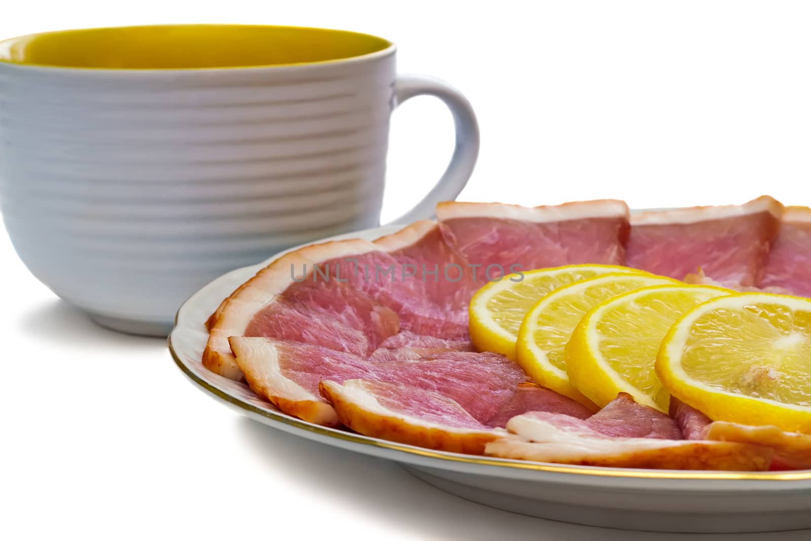 Delicious slices of ham and lemon to the dish and a big Cup. Presented on a white background.