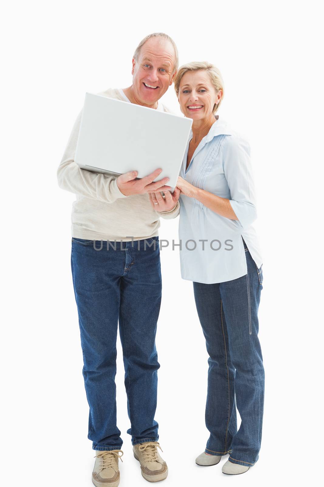 Mature couple smiling at camera with laptop on white background