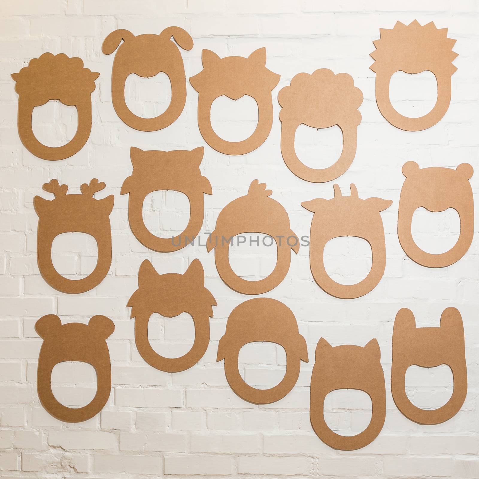 Set of cardboard masks on a white brick wall. by sarymsakov
