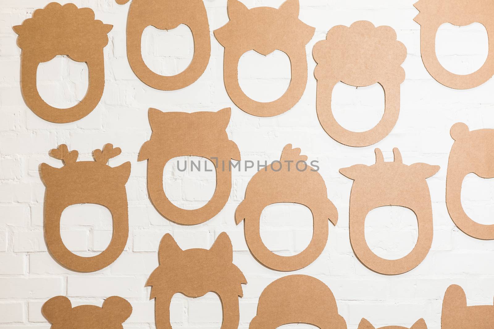 Set of cardboard masks on a white brick wall. by sarymsakov