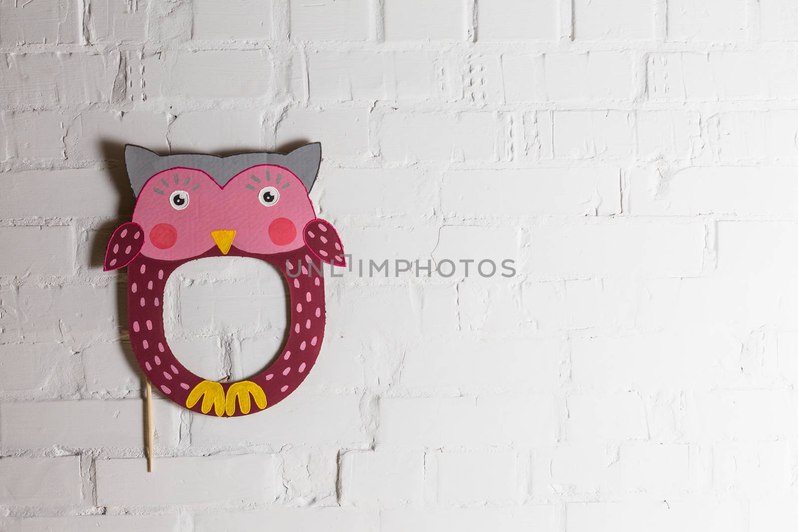 Bright cardboard mask on a white brick wall. Consept card. Owl