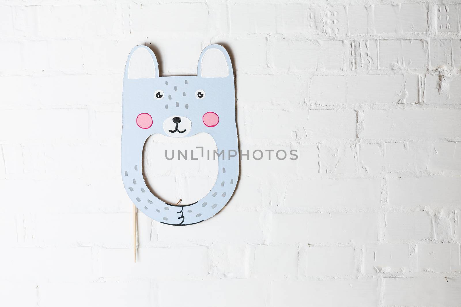 Bright cardboard mask on a white brick wall. Consept card. Rabbit