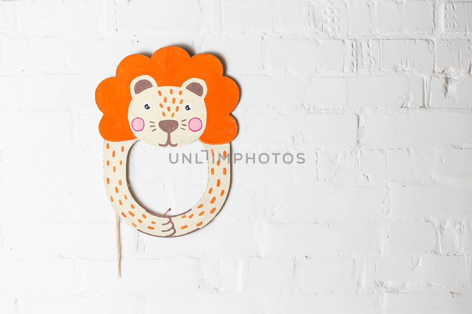 Bright cardboard mask on a white brick wall. Consept card. Lion