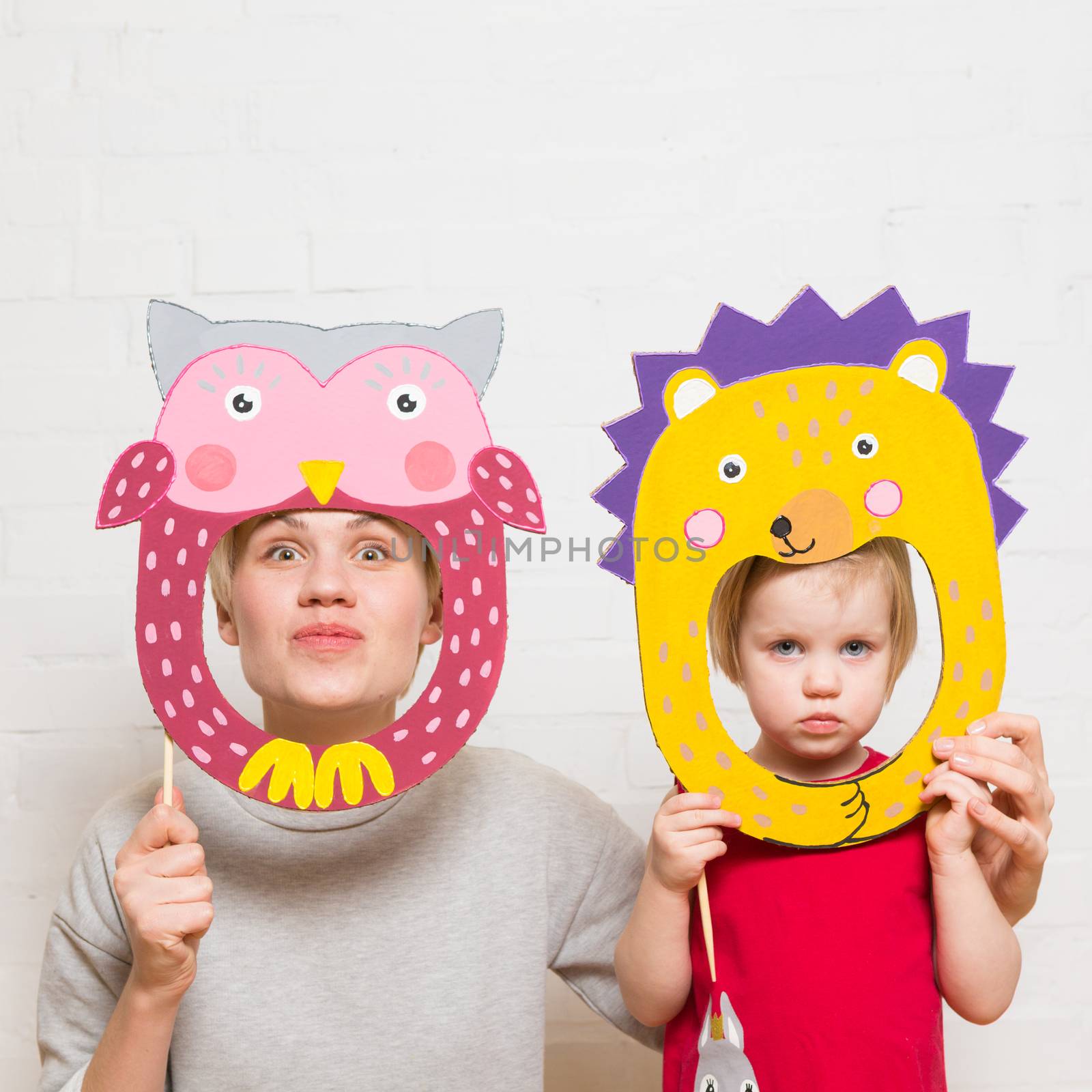 Little blonde girls and mother holding lion mask on white background
