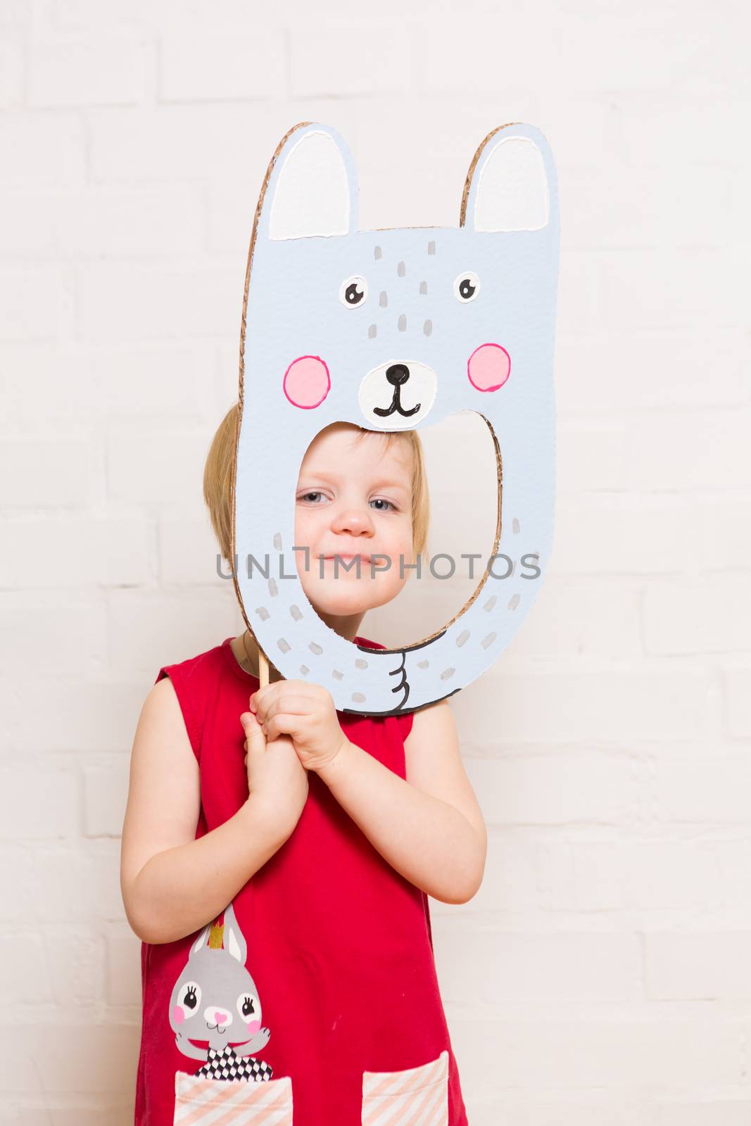 Little blonde girls holding rabbit mask on white background