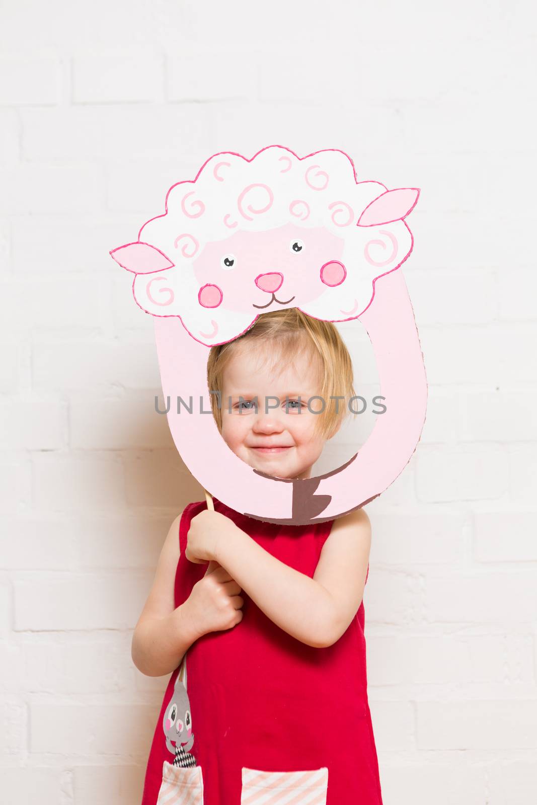 Little blonde girls holding sheep mask on white background