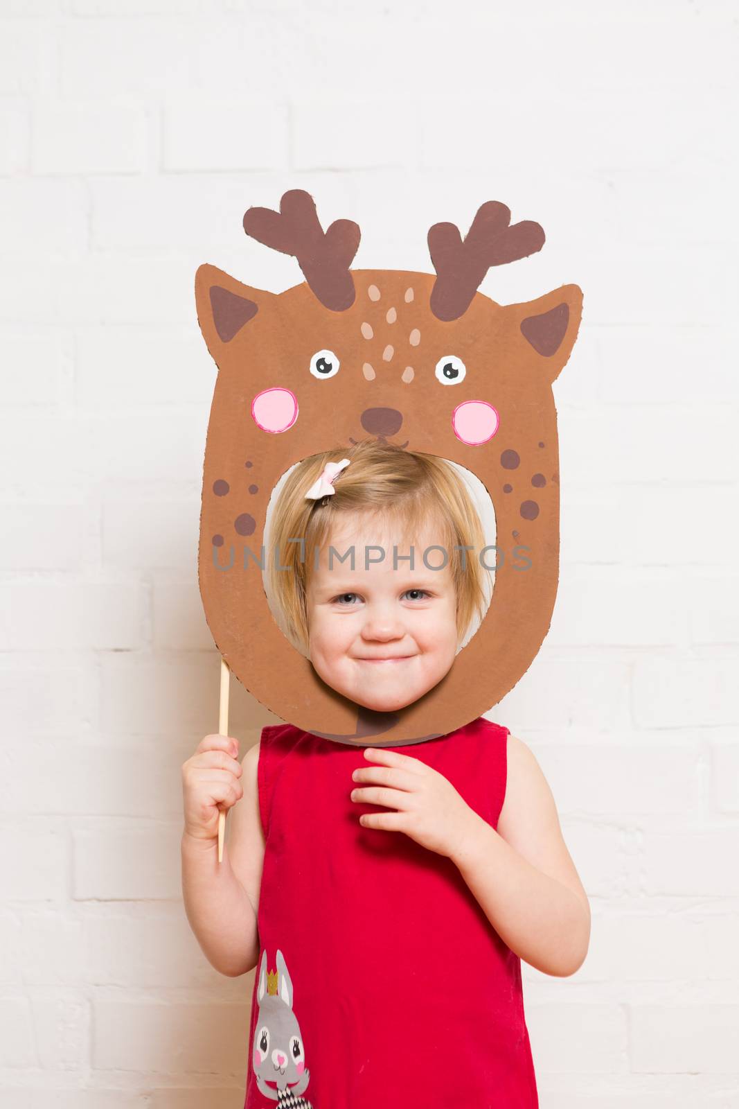 Little blonde girls holding deer mask on white background