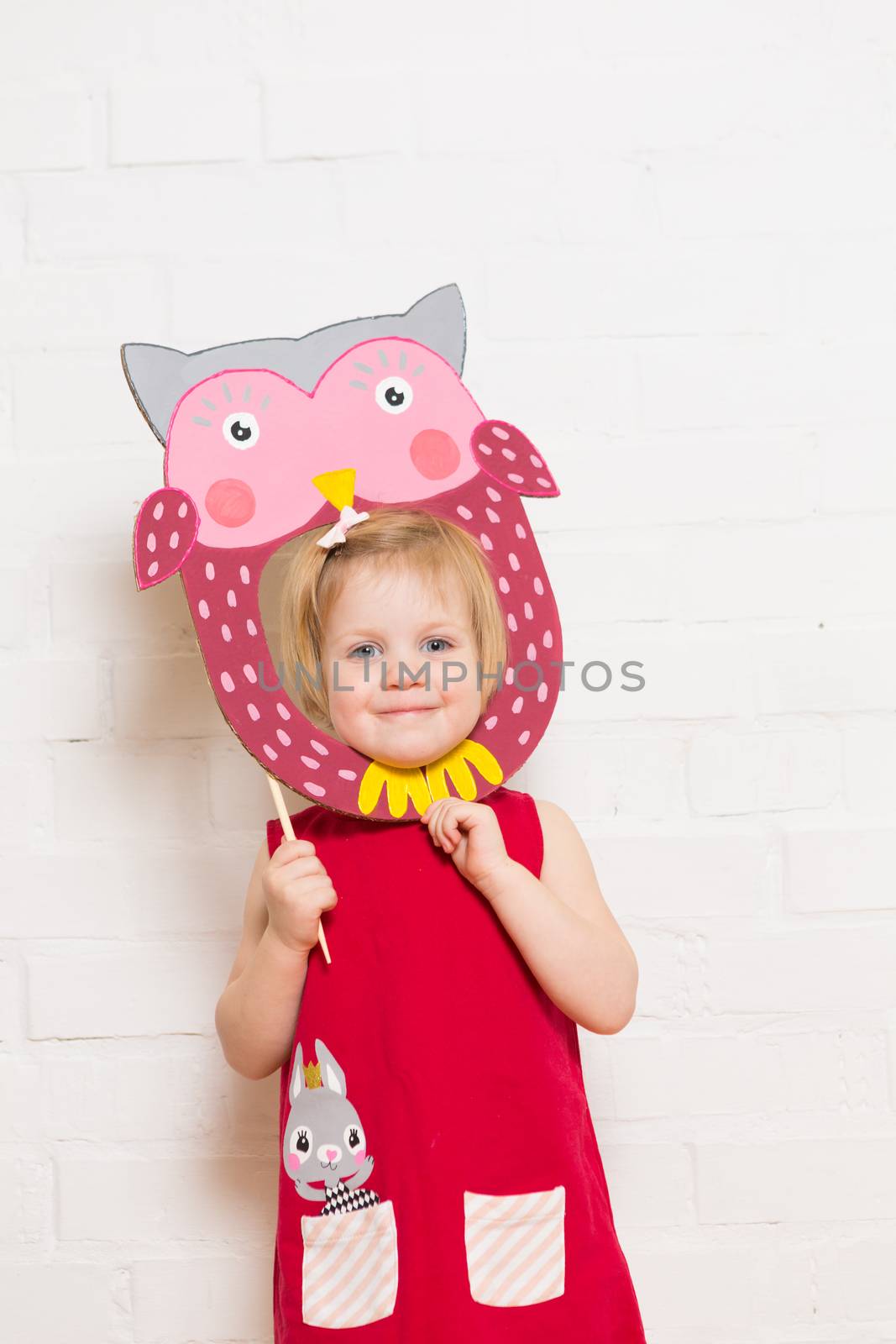 Little blonde girls holding owl mask on white background