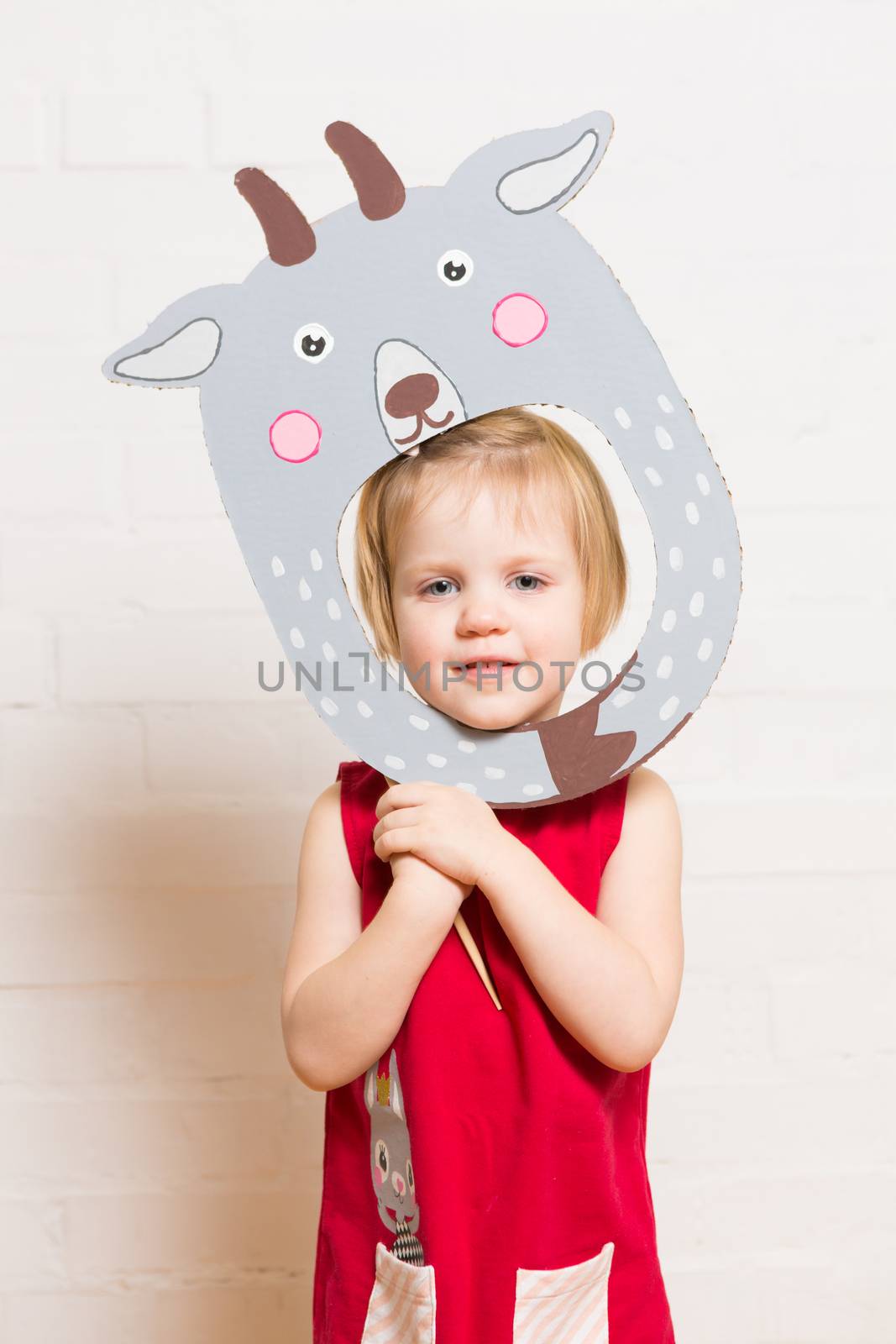 Little girls holding goat mask on white background by sarymsakov
