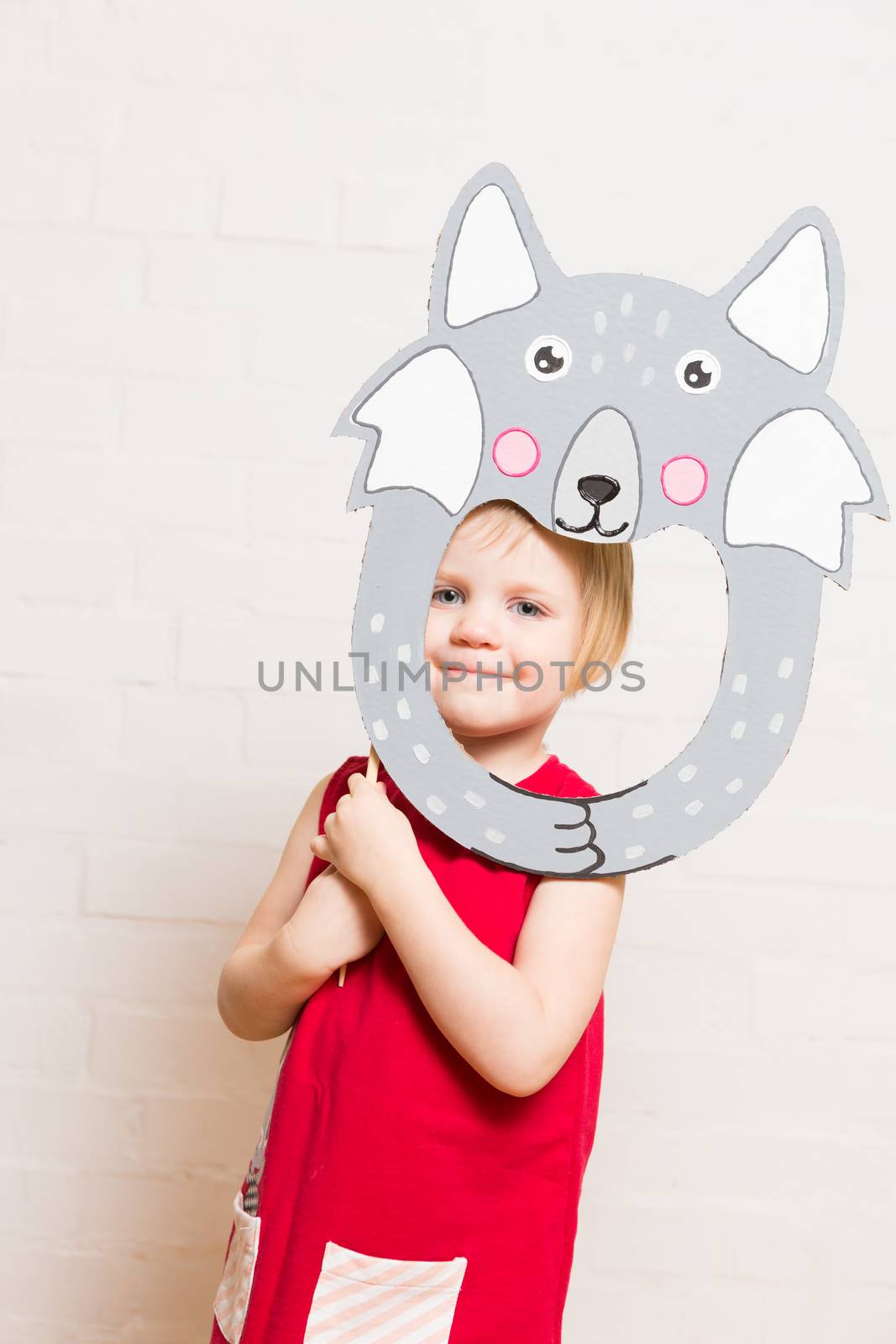 Little blonde girls holding wolf mask on white background