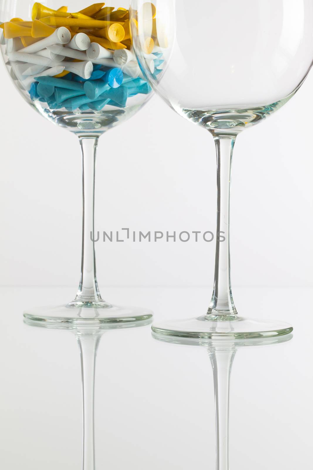 Two glasses of wine and golf equipments on the glass desk