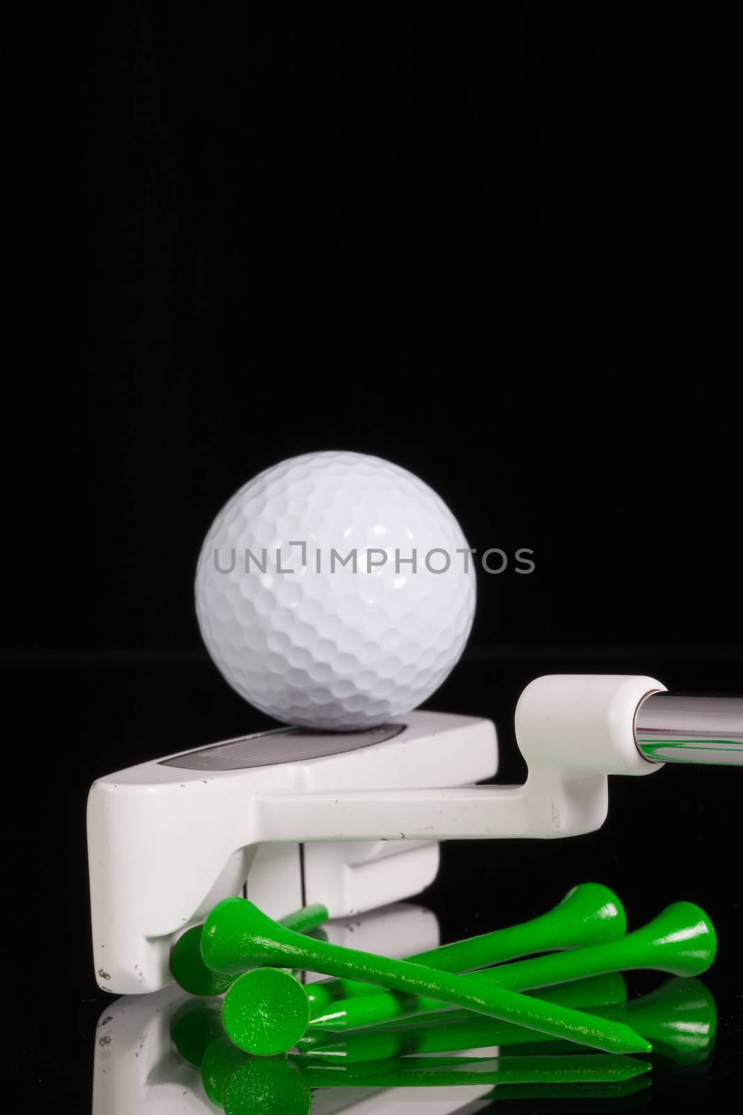 Golf putter and different golf equipments on the black glass desk