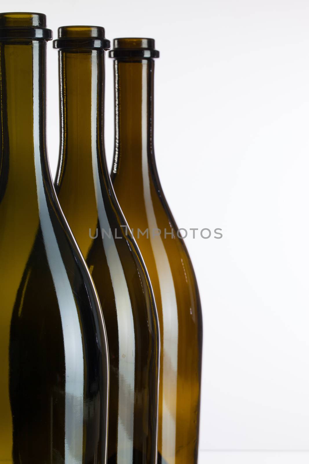 Three empty bottles of wine on a glass table