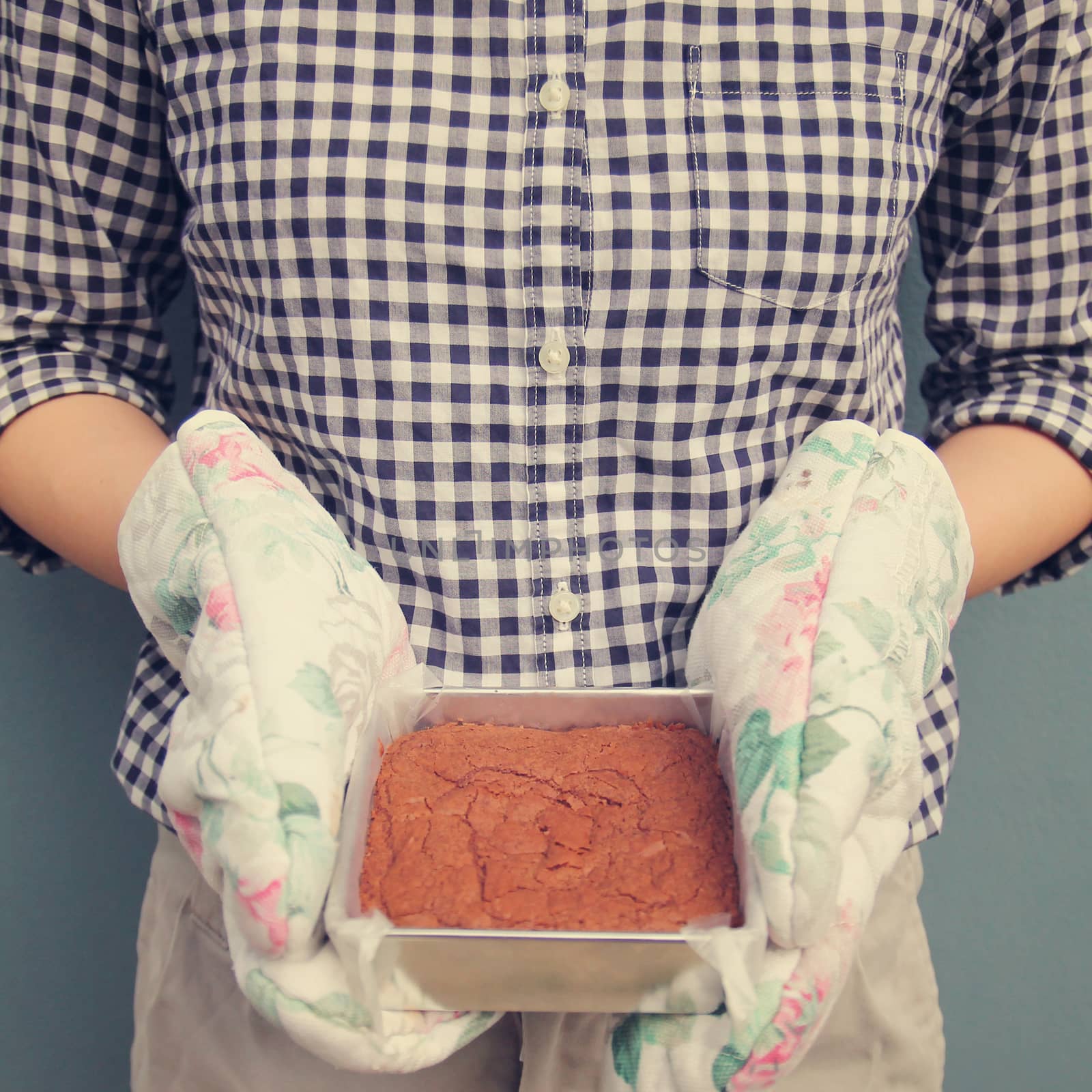 Woman holding brownie taken out of oven, retro filter effect