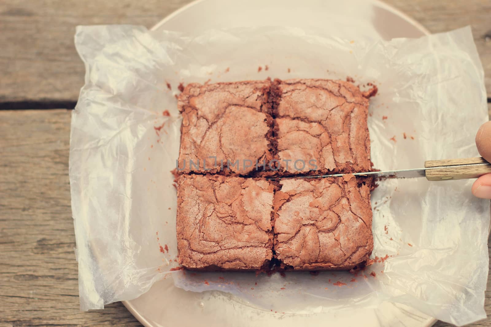 Cutting crispy homemade brownie with retro filter effect