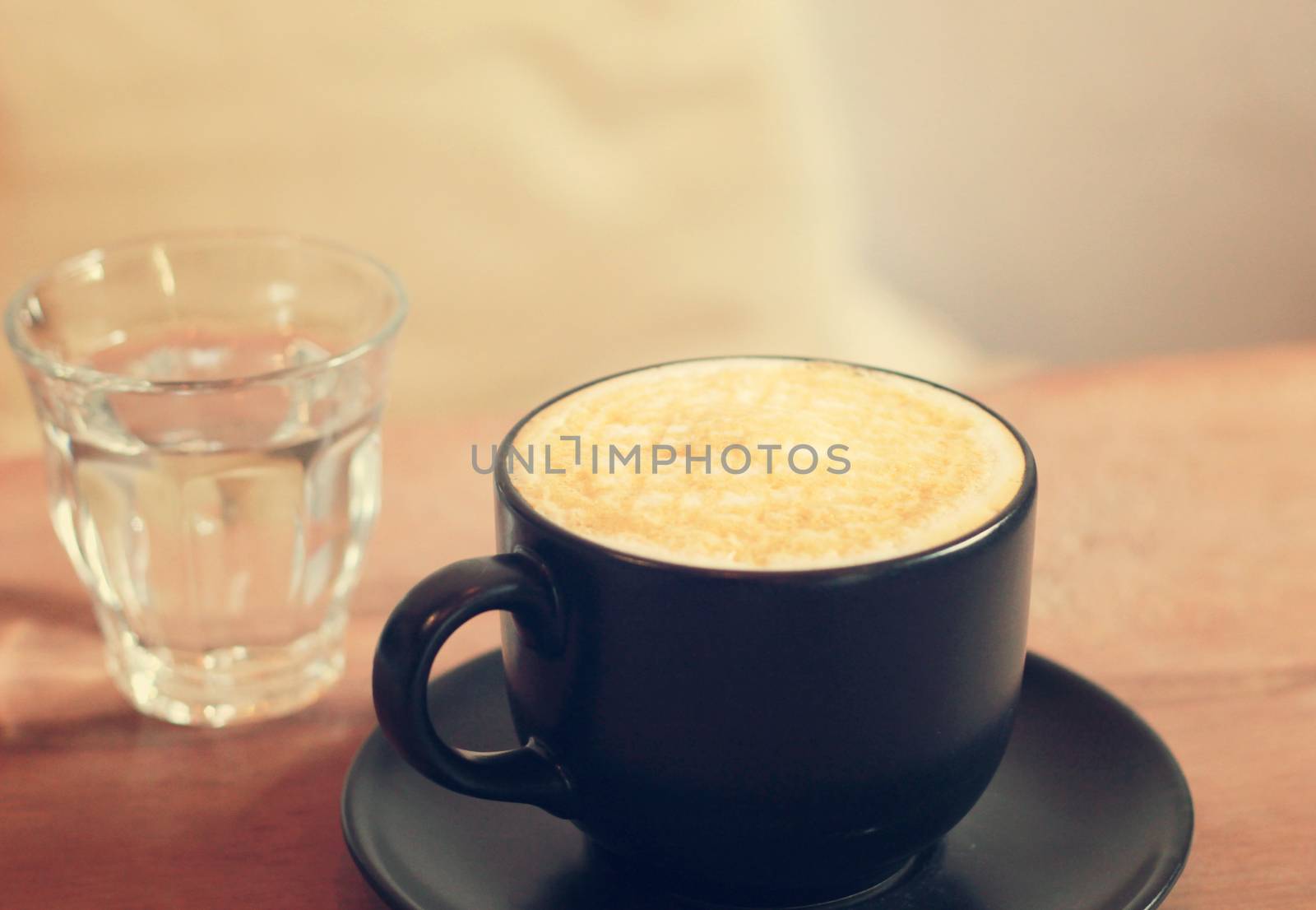 Hot cup of caramel macchiato with glass of water, retro filter e by nuchylee