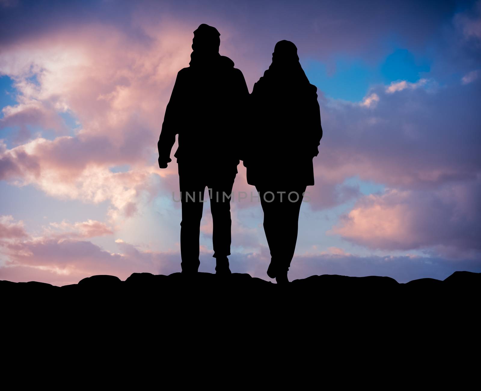 Silhouette Of A Couple Hiking On A Mountain Against Beautiful Sunset