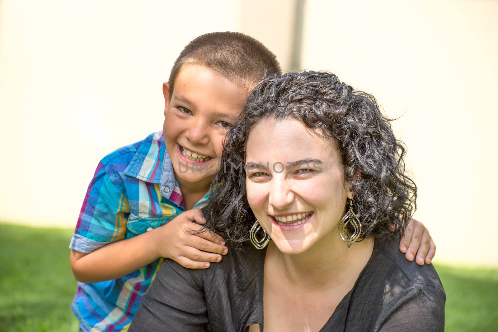 Mother and son outside in garden. both are happy, and smiling while son gives mother a hug.