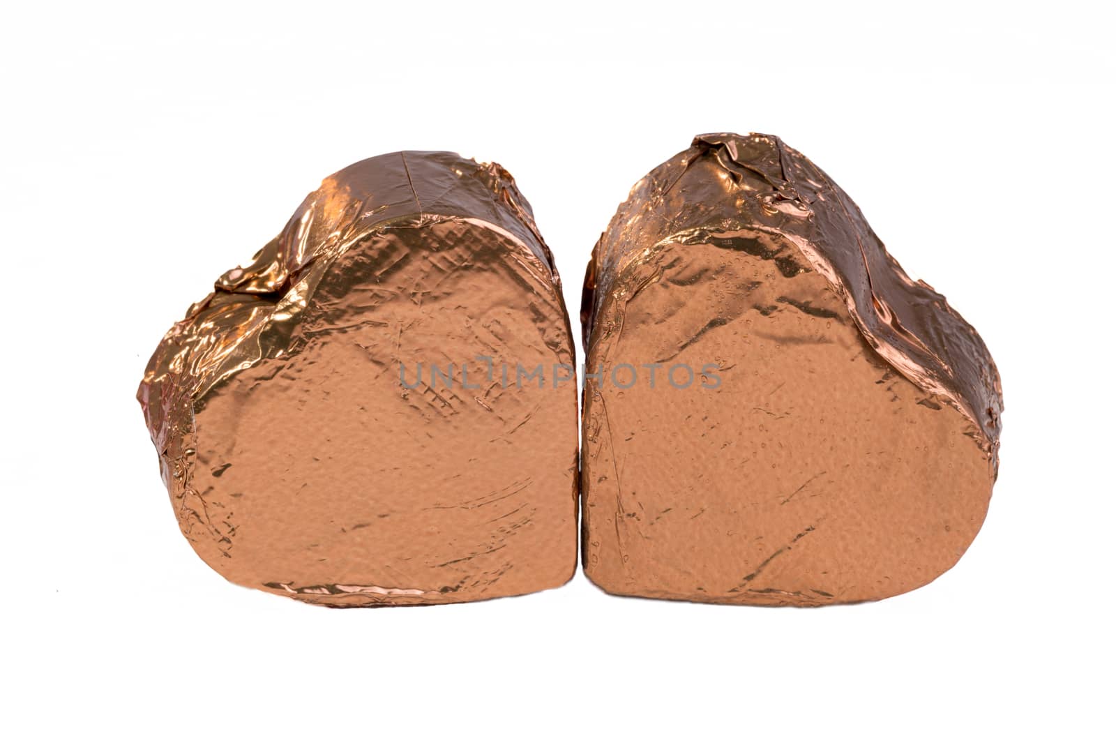 Two chocolate hearts together in brown wrapping foil, close to each other.