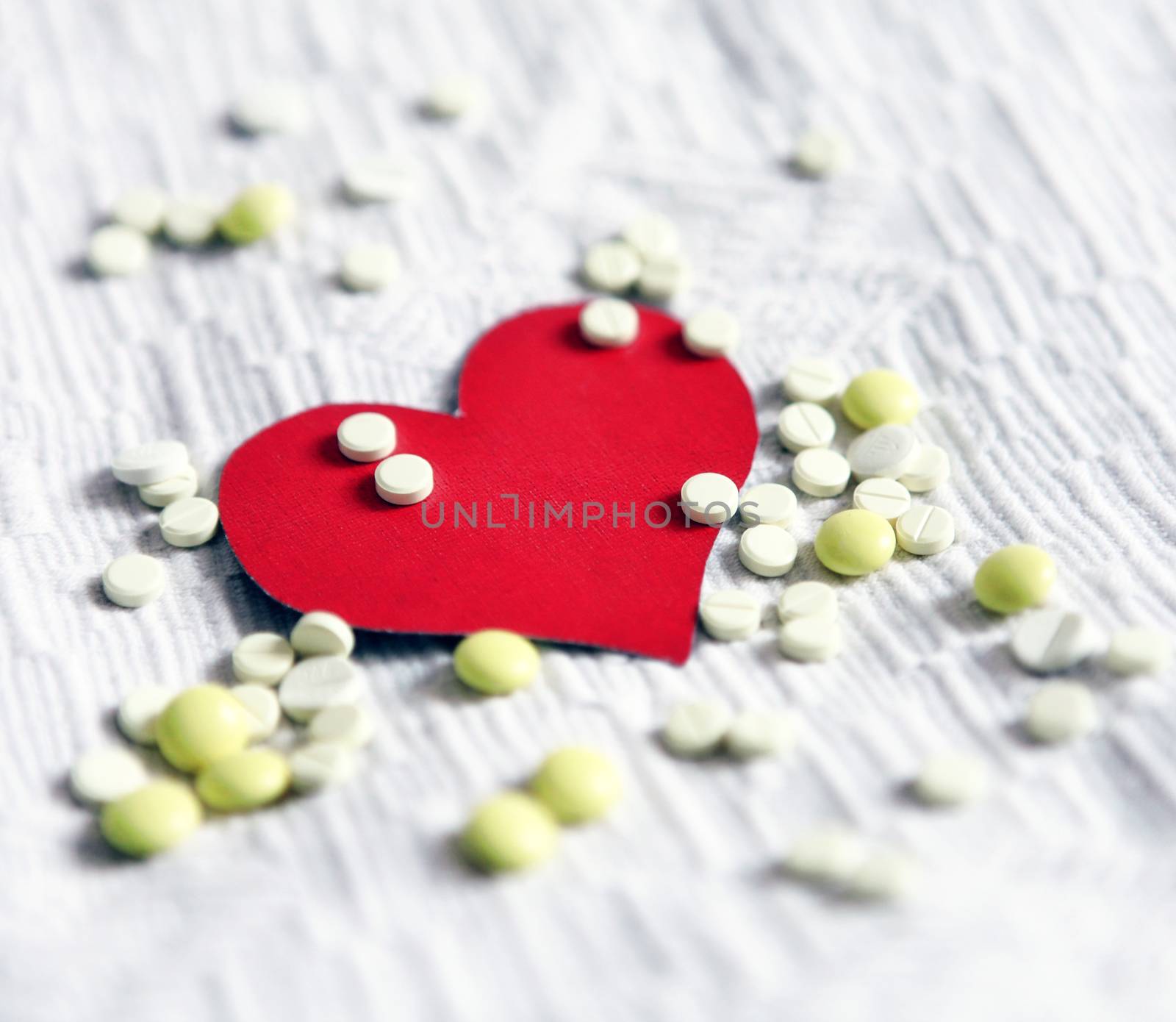 Heart Shape with the Pills on the White Fabric Background