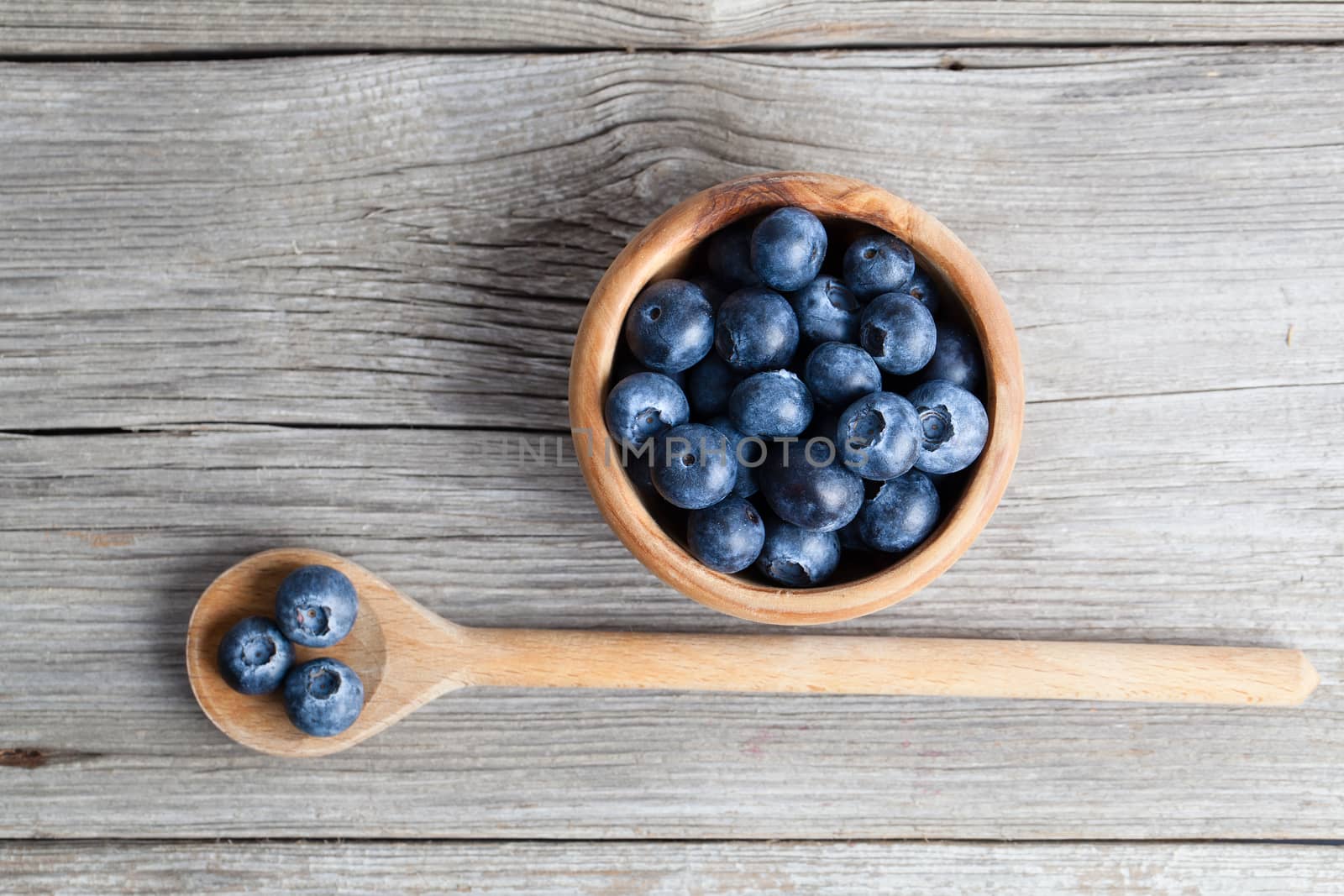 Blueberries on a wooden bowl, spoon. on wooden background