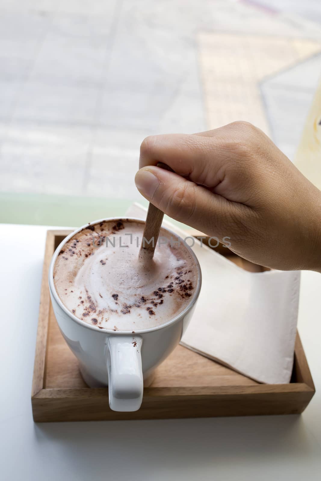 Human hand stir hot chocolate in cafe
