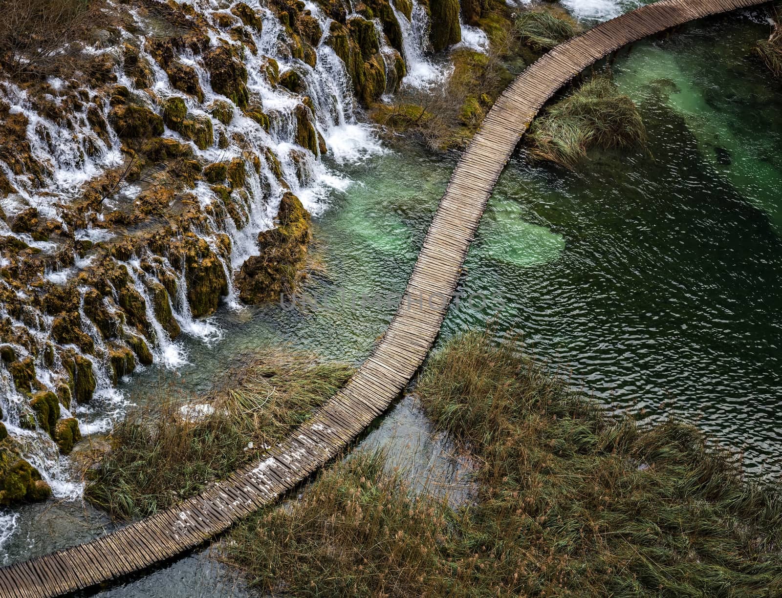 Diagonally separating waterfalls and river wooden catwalk 