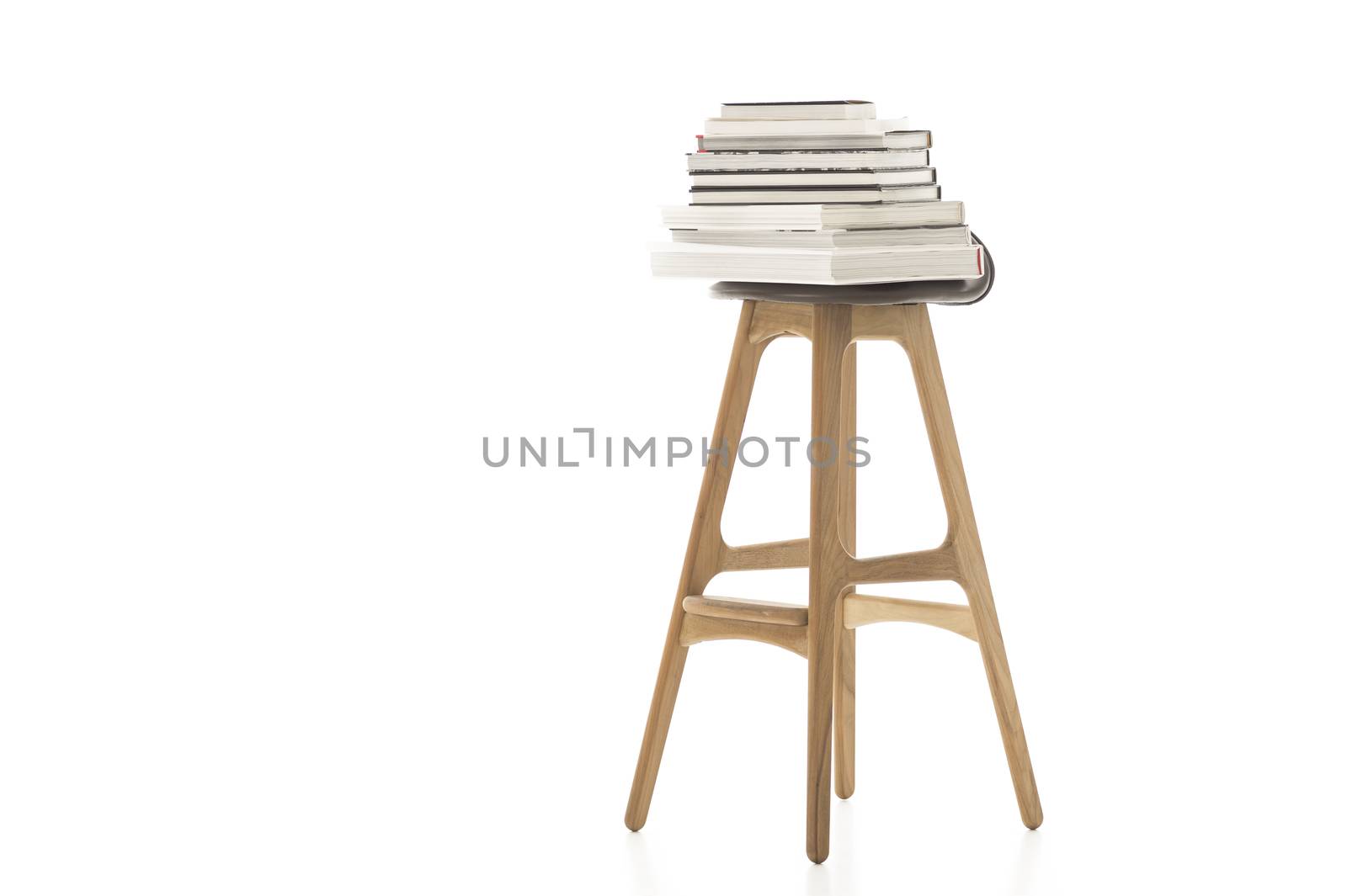 Conceptual Pile of Books on Top of Wooden Leg Chair Isolated on White Background. Emphasizing White Background.