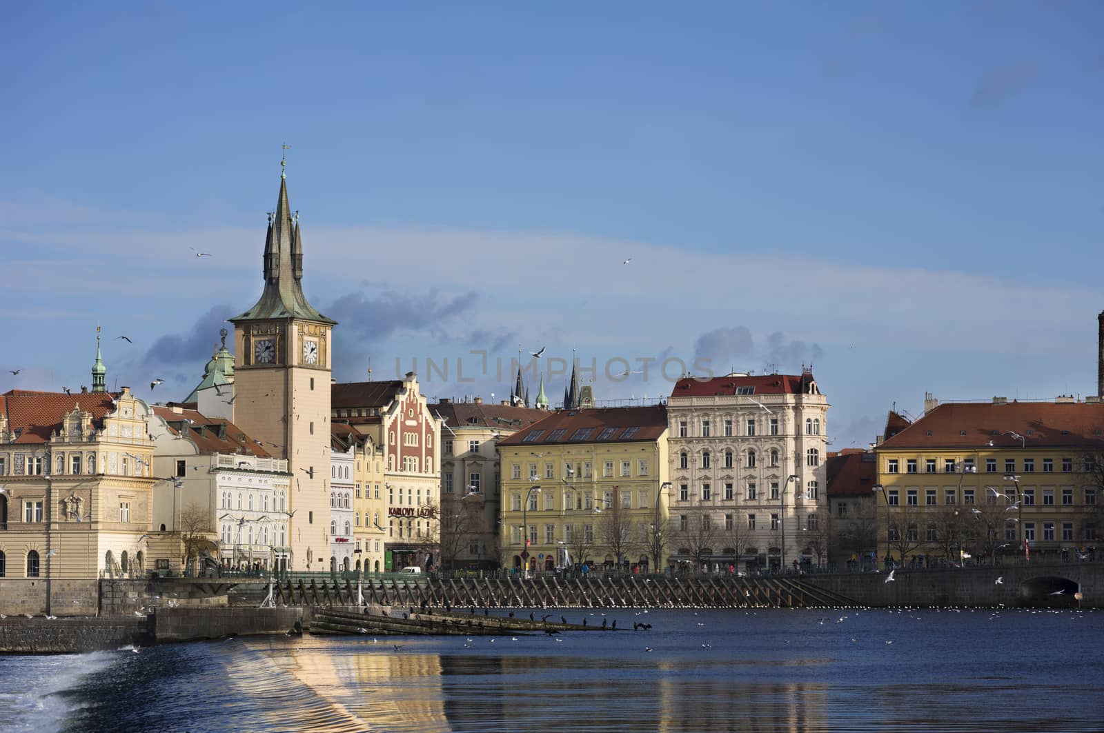 Beautiful gothic building on the bank of the river Vltava in Prague under a vivid blue sky.