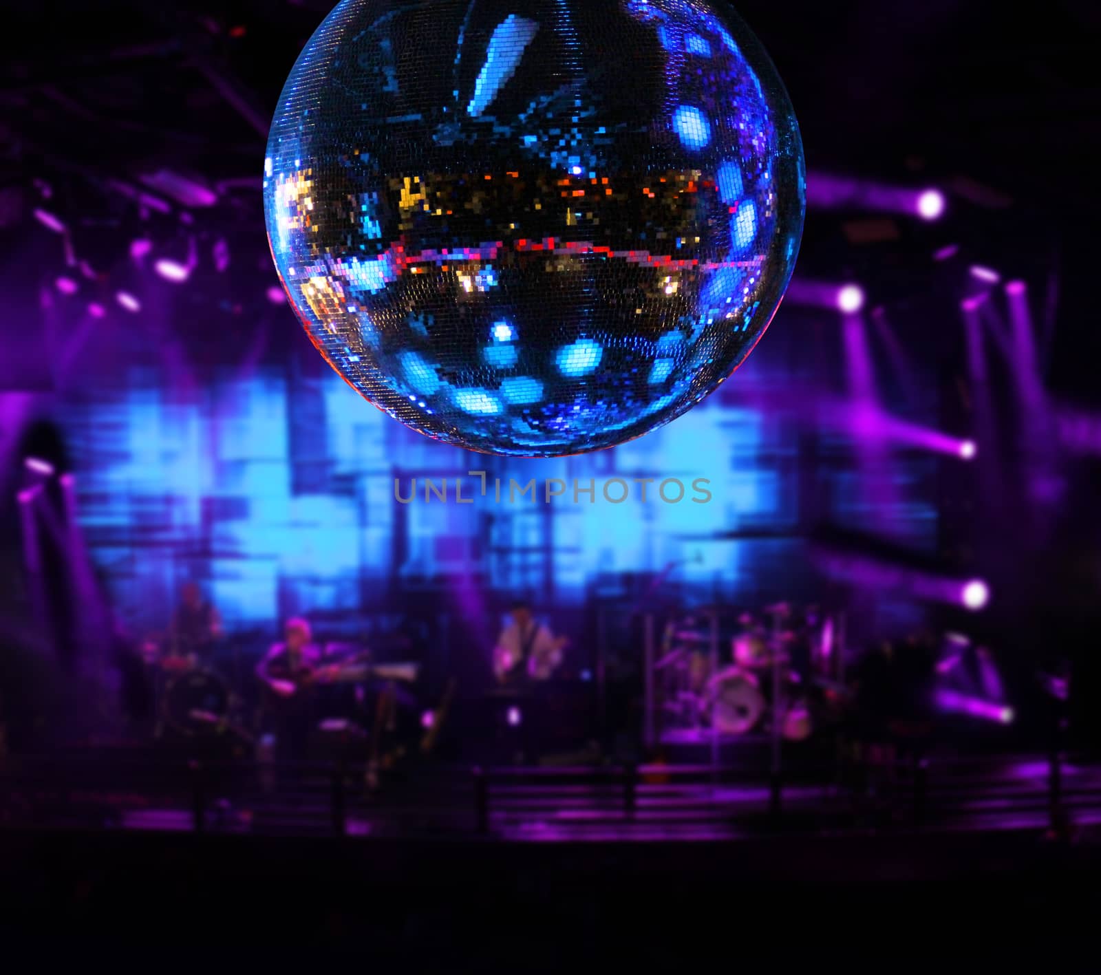 Band playing under disco mirror ball color lights