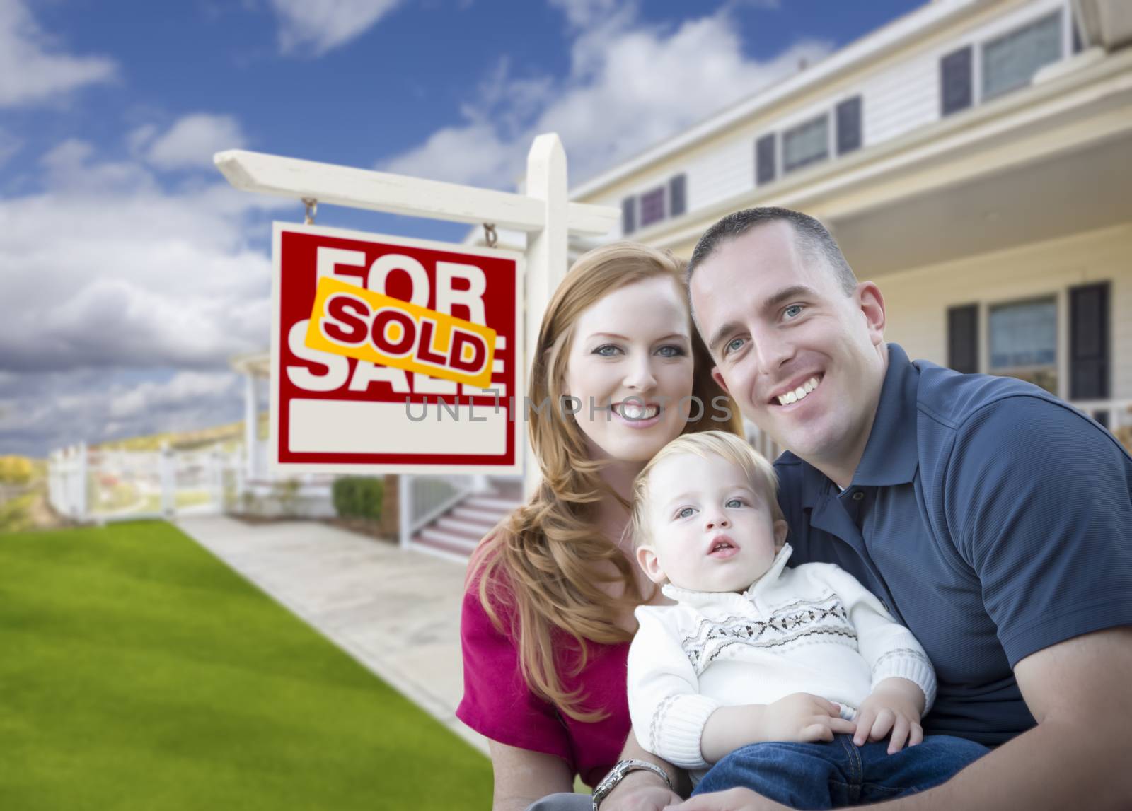 Happy Young Military Family in Front of Sold Real Estate Sign and New House.