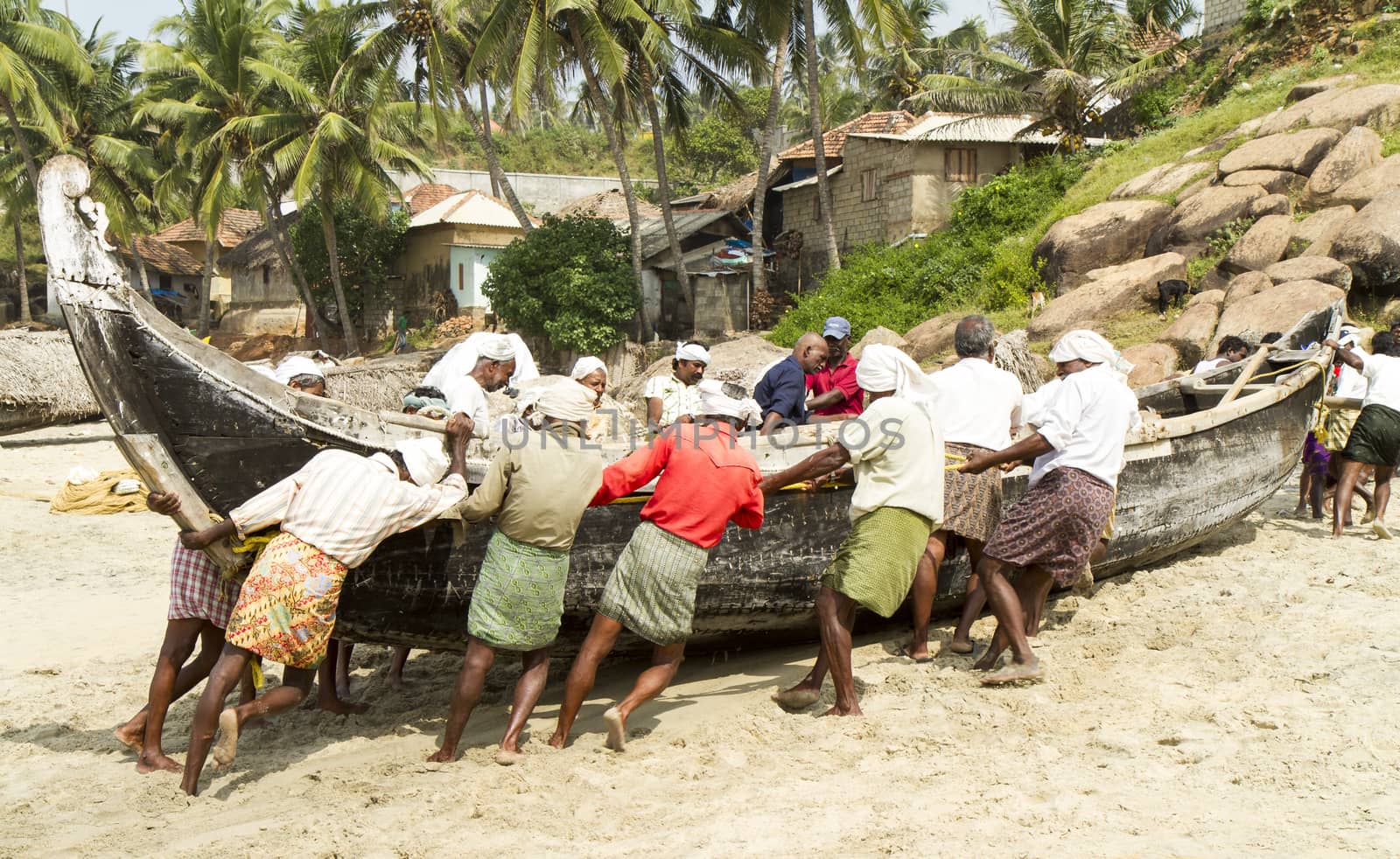 Fishermen pushing the fishing boat on the beach (Kerala, India)