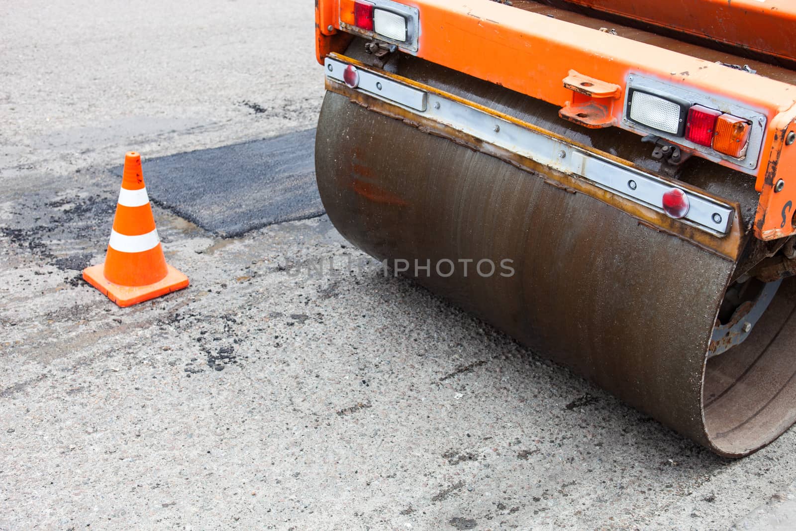 Road roller and traffic cone on the road construction.