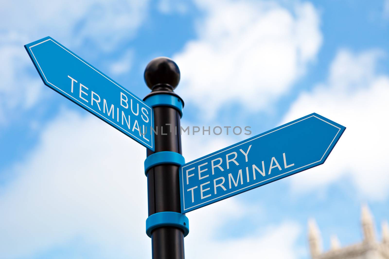 Blue bus and ferry terminal sign in front of a clouded blue sky.