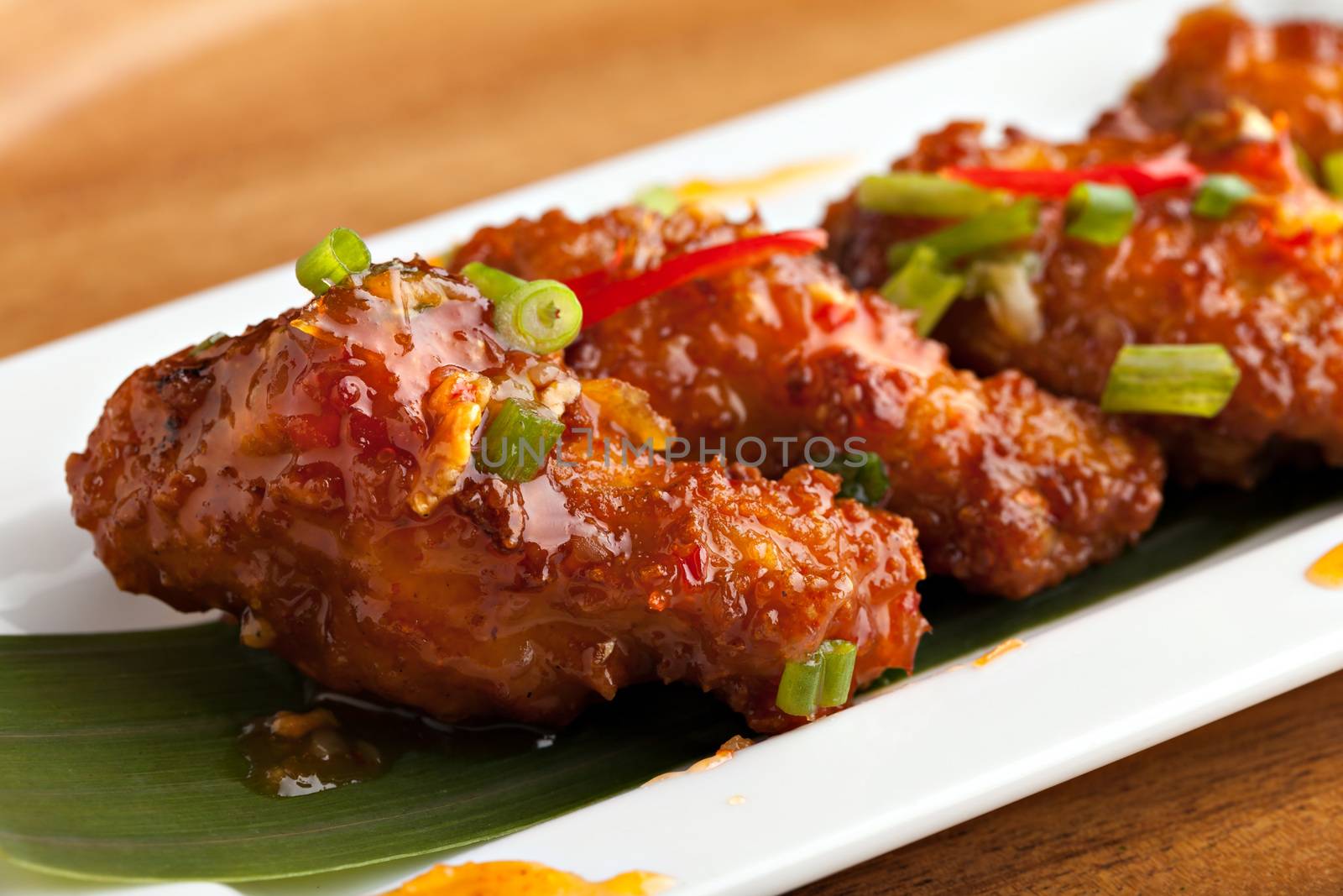 Thai style spicy chicken wings appetizer on a contemporary white plate.