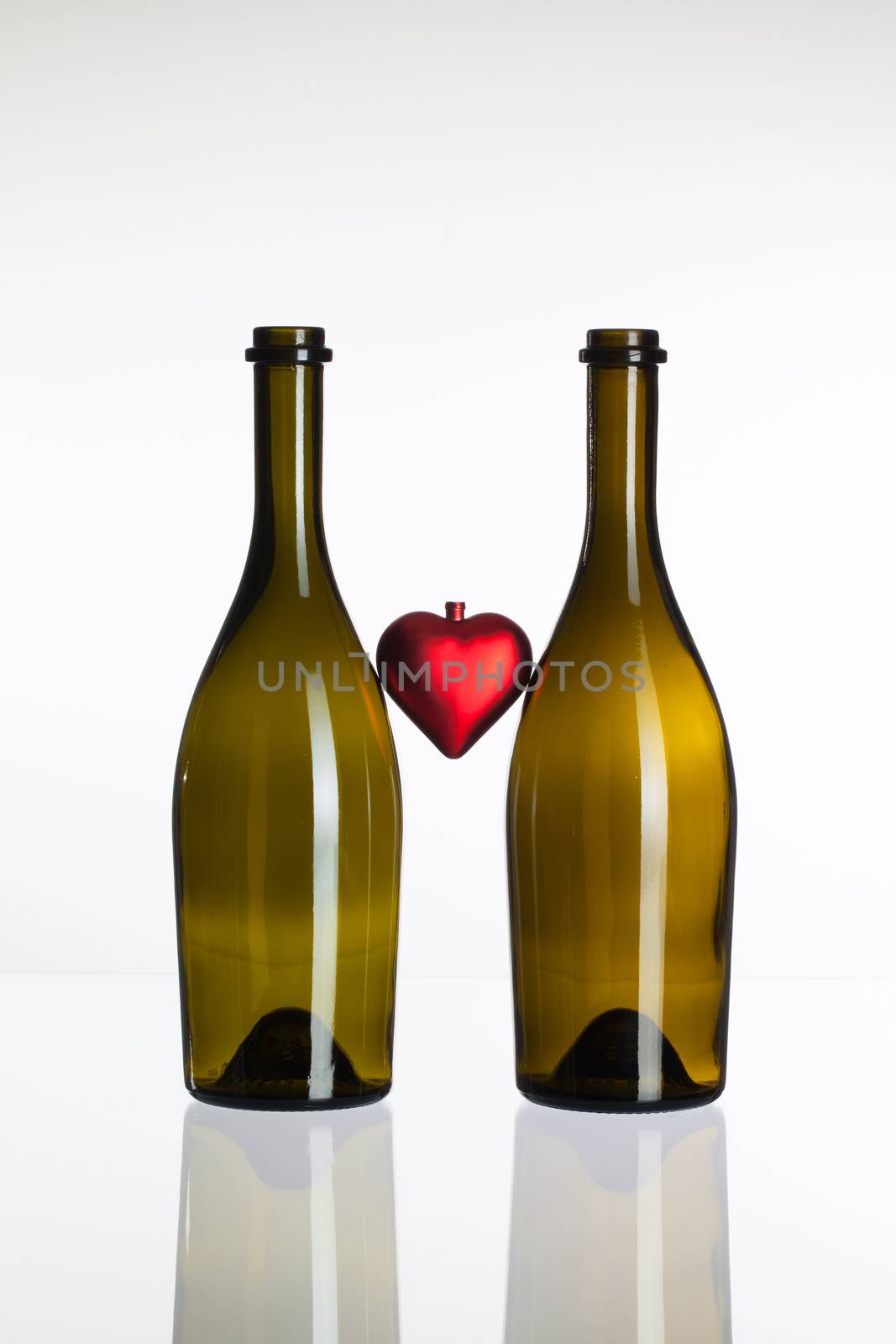 Empty bottles of wine and red heart on a glass table