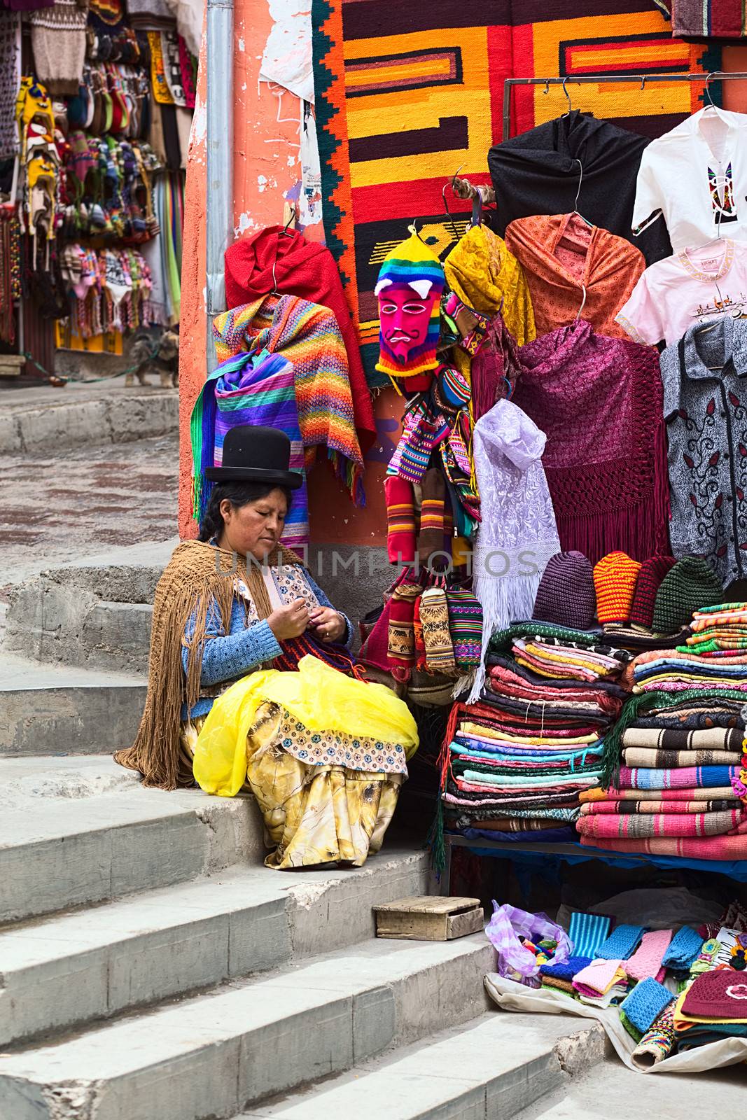LA PAZ, BOLIVIA - NOVEMBER 10, 2014: Unidentified woman doing crochet sitting on the stairs beside her small street stand on the corner of the streets Sagarnaga and Linares in the city center on November 10, 2014 in La Paz, Bolivia