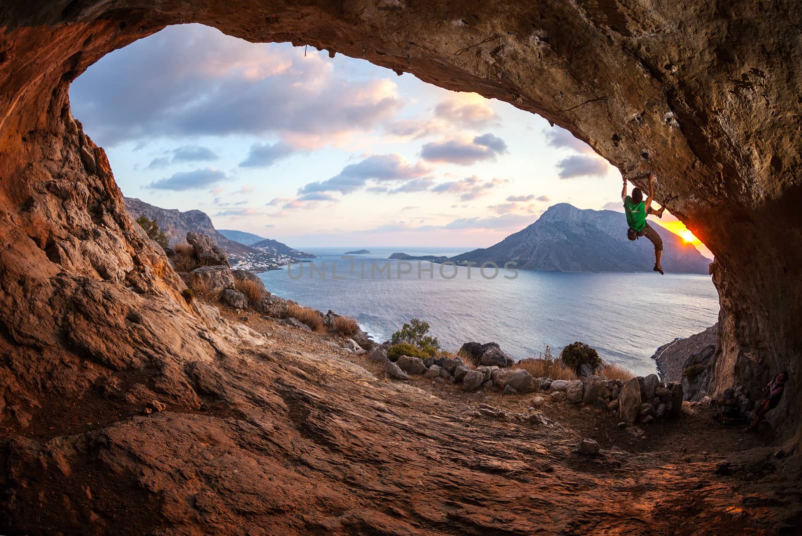 Male rock climber climbing along a roof in a cave by photobac